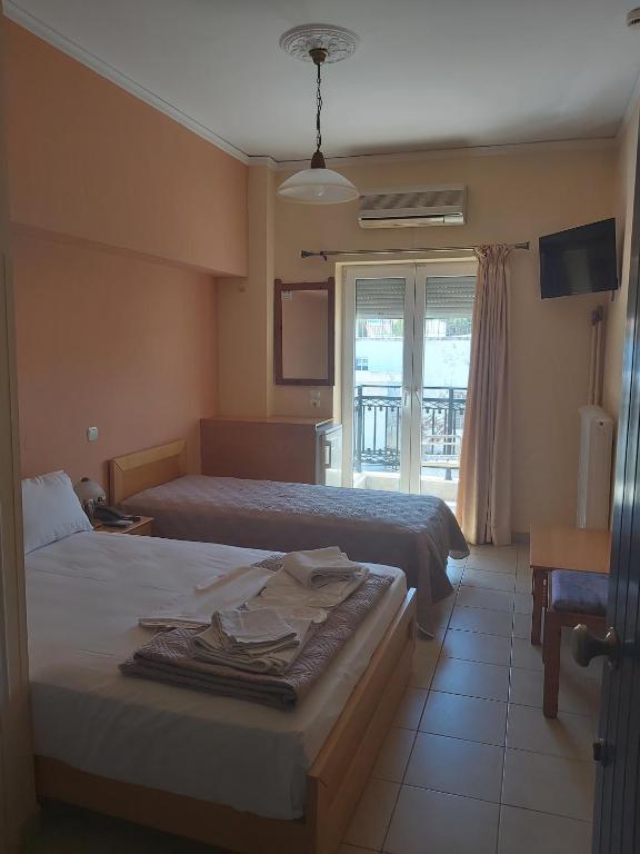 a hotel room with two beds and a window at Zoumboulis Rooms in Mytilene