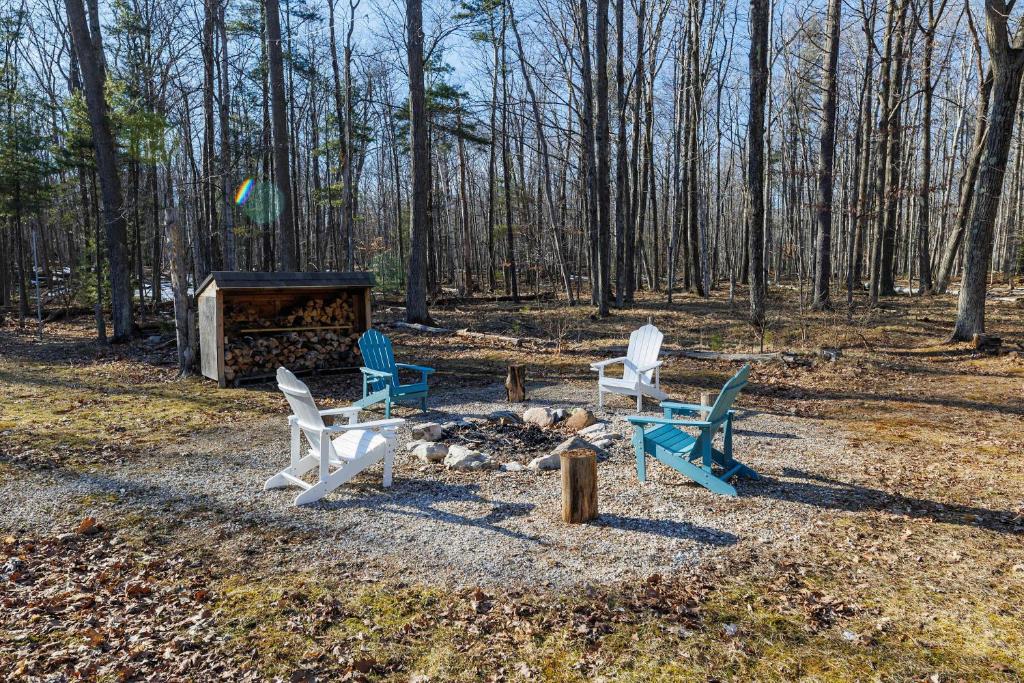 three chairs sitting around a fire in the woods at The Roost by Simple Life Rentals in Baileys Harbor