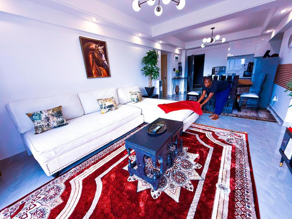 a woman in a living room with a white couch at SPOTLESS HOSTEL, WESTLANDs Orc in Nairobi
