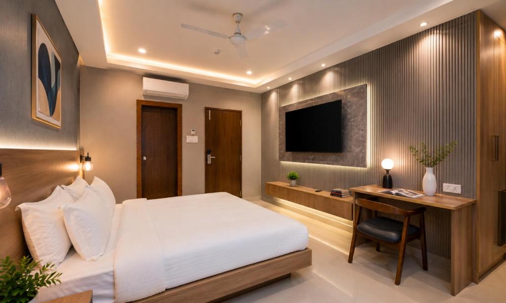 a bedroom with a bed and a desk and a television at Harvey's Suites in Gachibowli