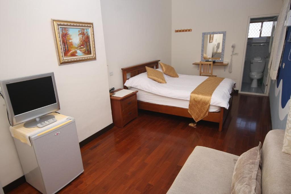 a small bedroom with a bed and a television at Sunrise B&amp;B in Huxi