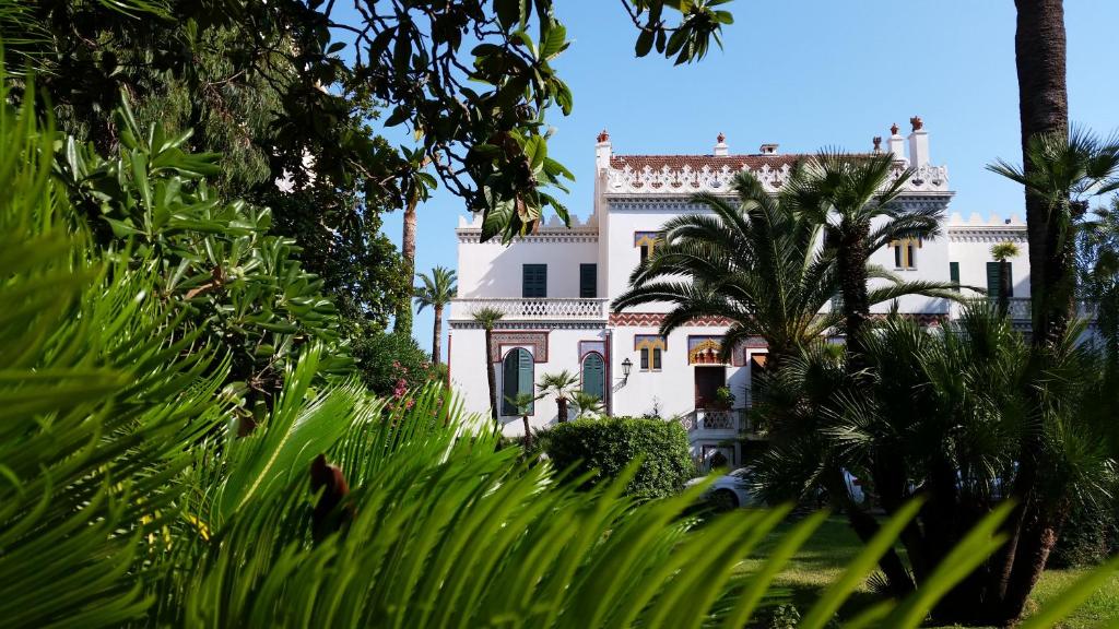 une maison blanche avec des palmiers devant elle dans l'établissement Villa Belle Rive, à Cannes
