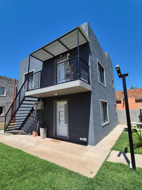 a gray house with a balcony and a staircase at Colibrí in Merlo