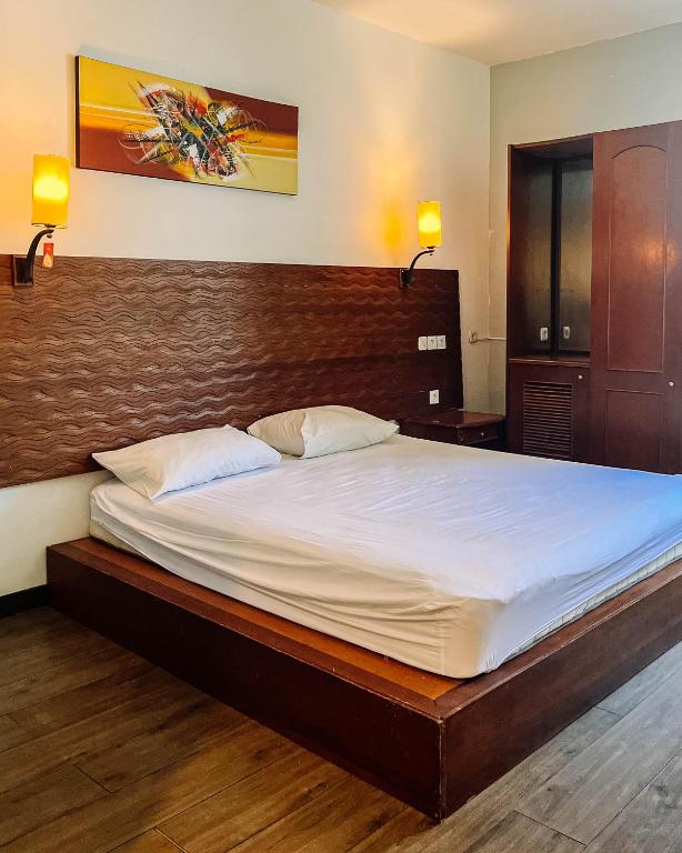 a bedroom with a large bed with a wooden headboard at Vu Exclusive Boarding House in Kerobokan