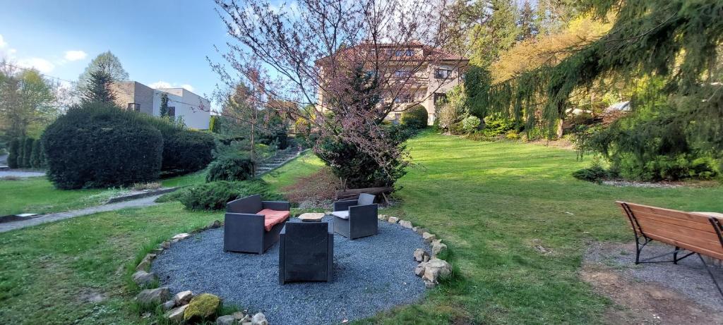 a park with a bench and chairs in the grass at Apartmán U splavu Luhačovice in Luhačovice