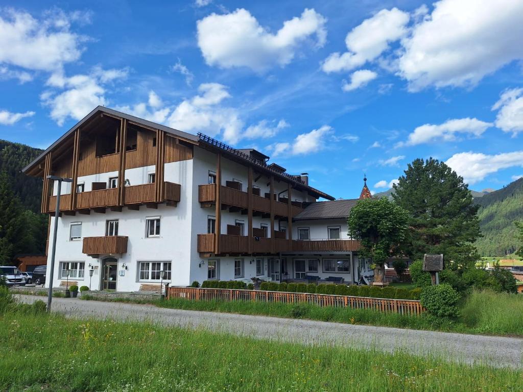 a large white building with wooden balconies at Hotel Pörnbacher in Valdaora