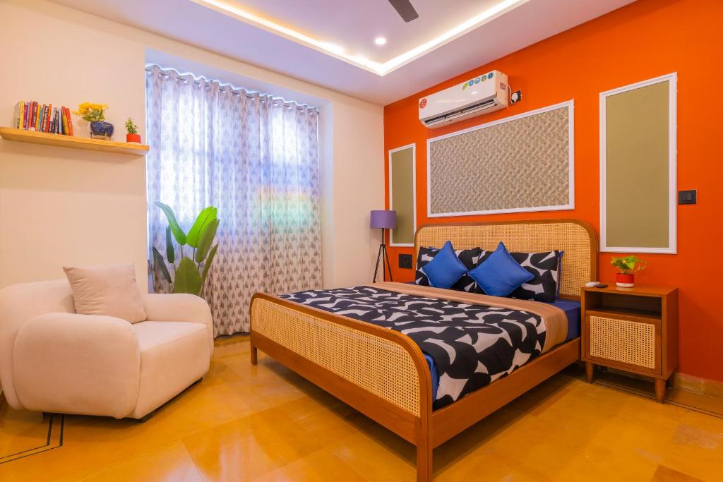 a bedroom with orange walls and a bed and a chair at Footprint Hostel Udaipur in Udaipur