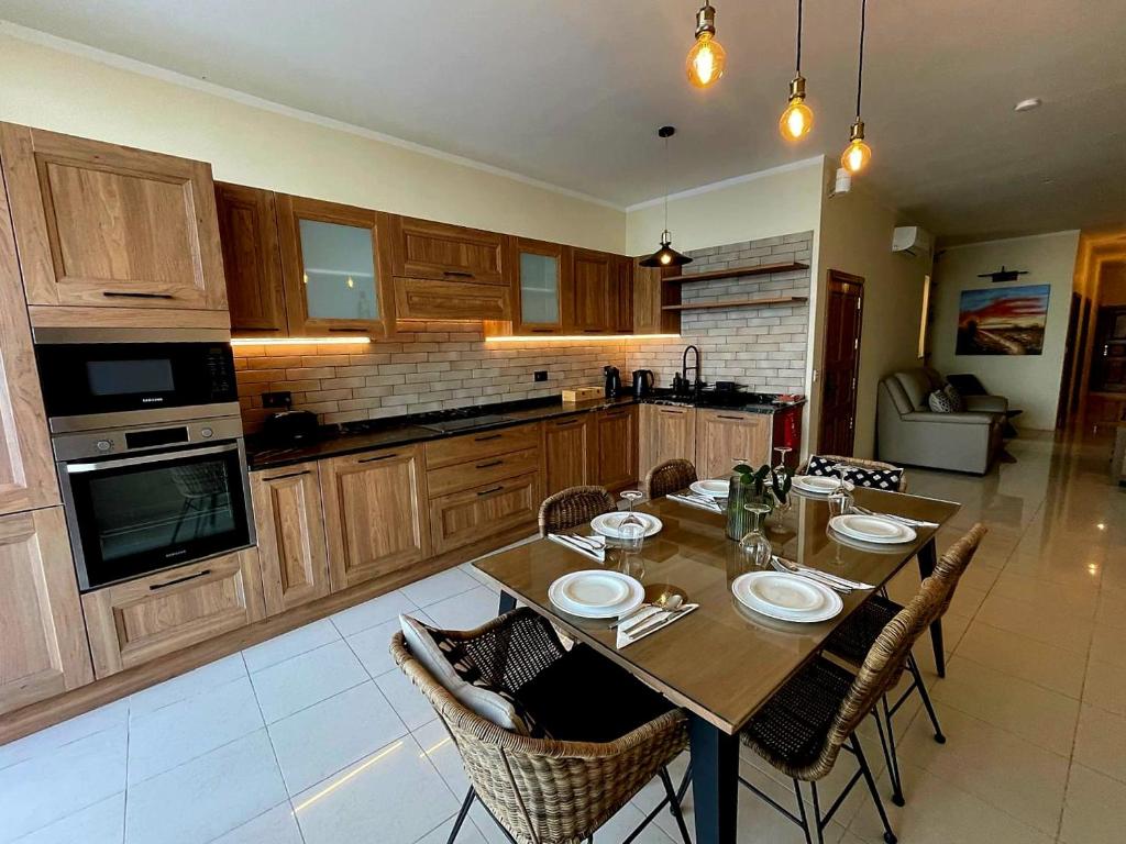 a kitchen with a wooden table with chairs and a tableasteryasteryasteryasteryastery at Salty Sun Seafront Penthouse in Marsalforn