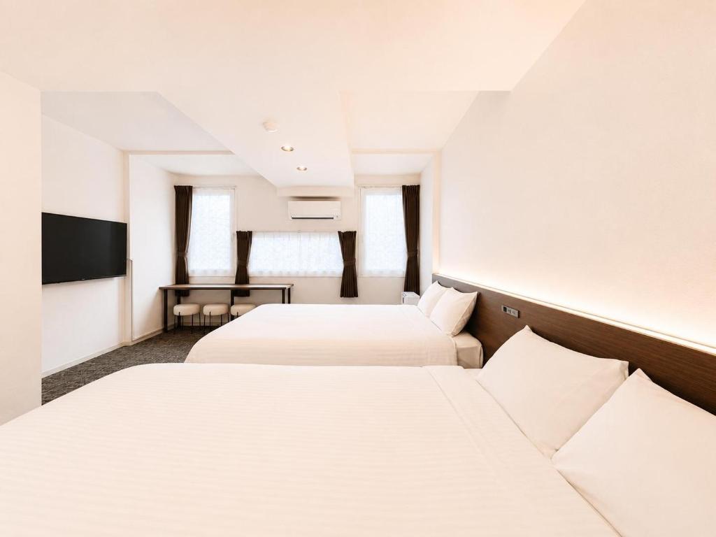 a hotel room with two beds and a tv at Residence Hotel Liberte in Sapporo