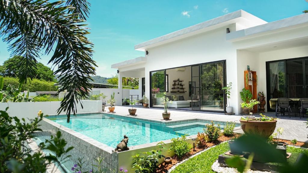 a villa with a swimming pool in front of a house at Villa des Princes in Ban Thung