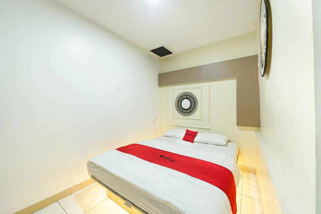 a bedroom with a white bed with a red blanket at JM Guest House Lamaran RedPartner in Karawang