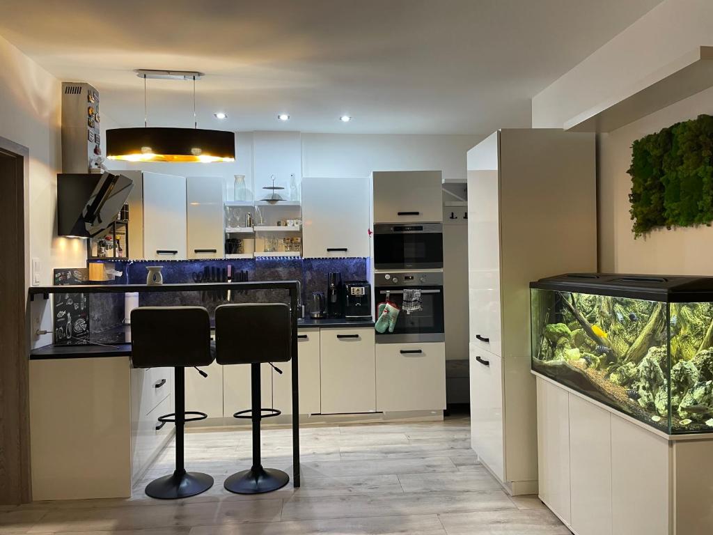 a kitchen with a fish tank and two bar stools at Apartmán SIA Garážové parkovanie in Poprad