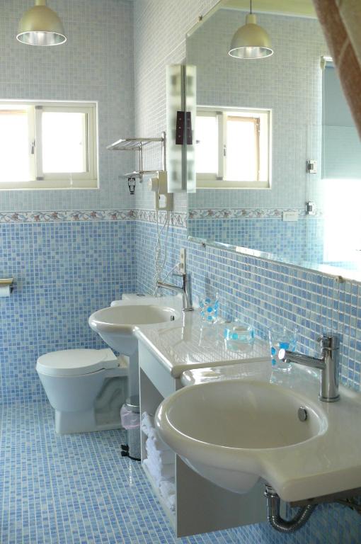 a blue tiled bathroom with two sinks and a toilet at Sunrise B&amp;B in Huxi