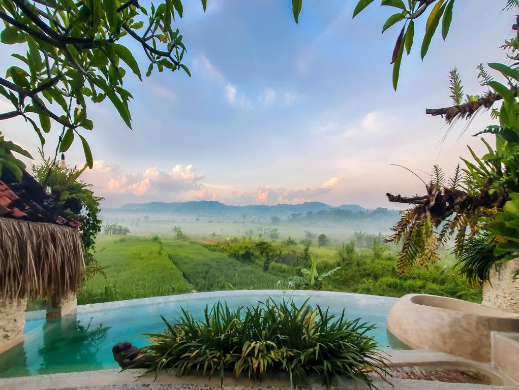 a pool in a garden with a view of the mountains at HAVAN Villas - Yogyakarta in Jarakan