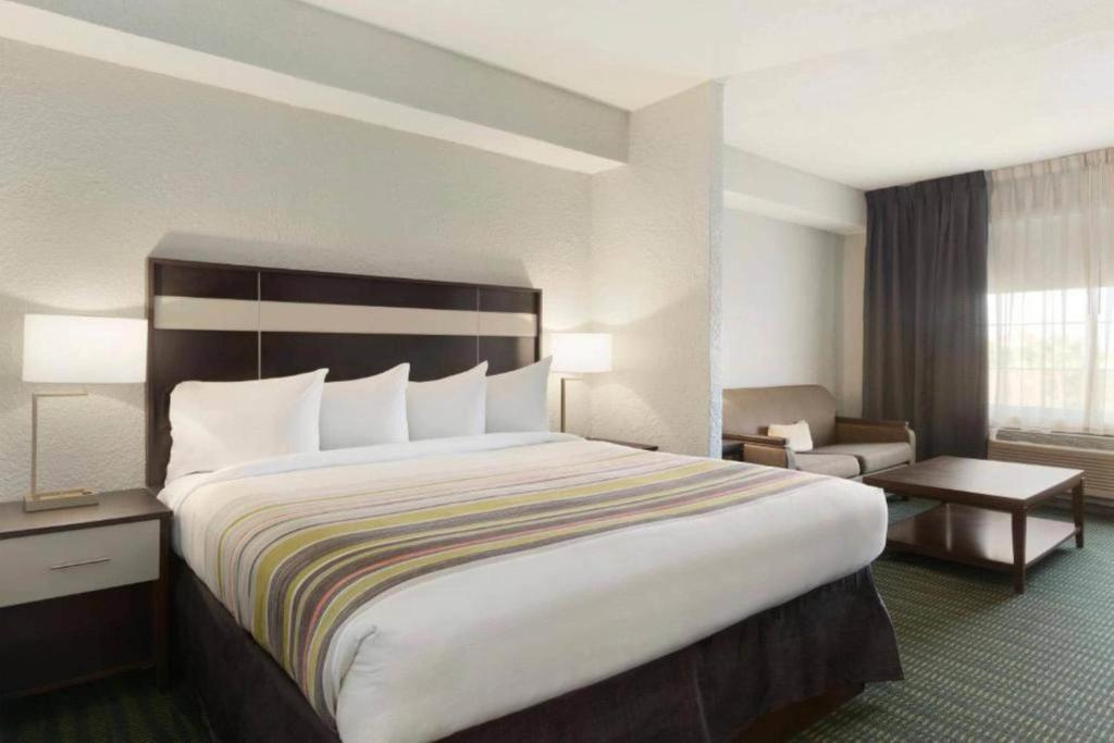 a hotel room with a large bed and a chair at Hotel Flamingo Inn & Suites Vero Beach I-95 in Vero Beach