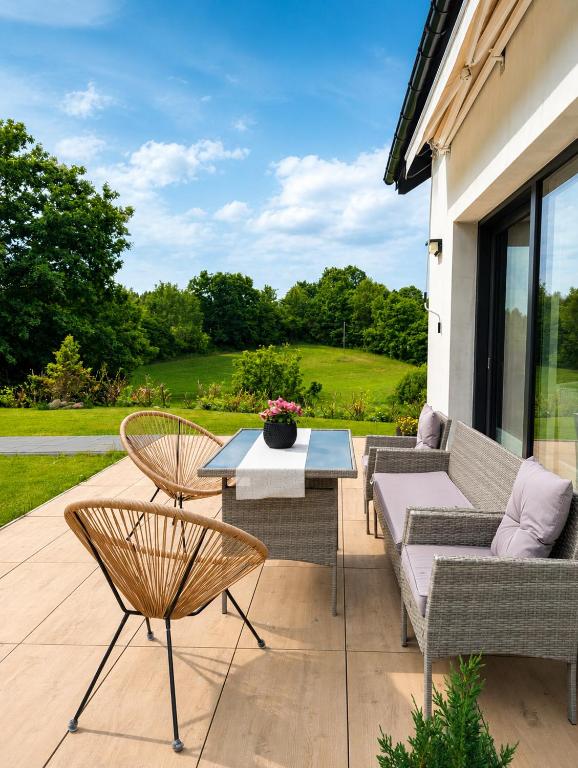 a patio with a couch and chairs and a table at Skośne Domki in Chmielno