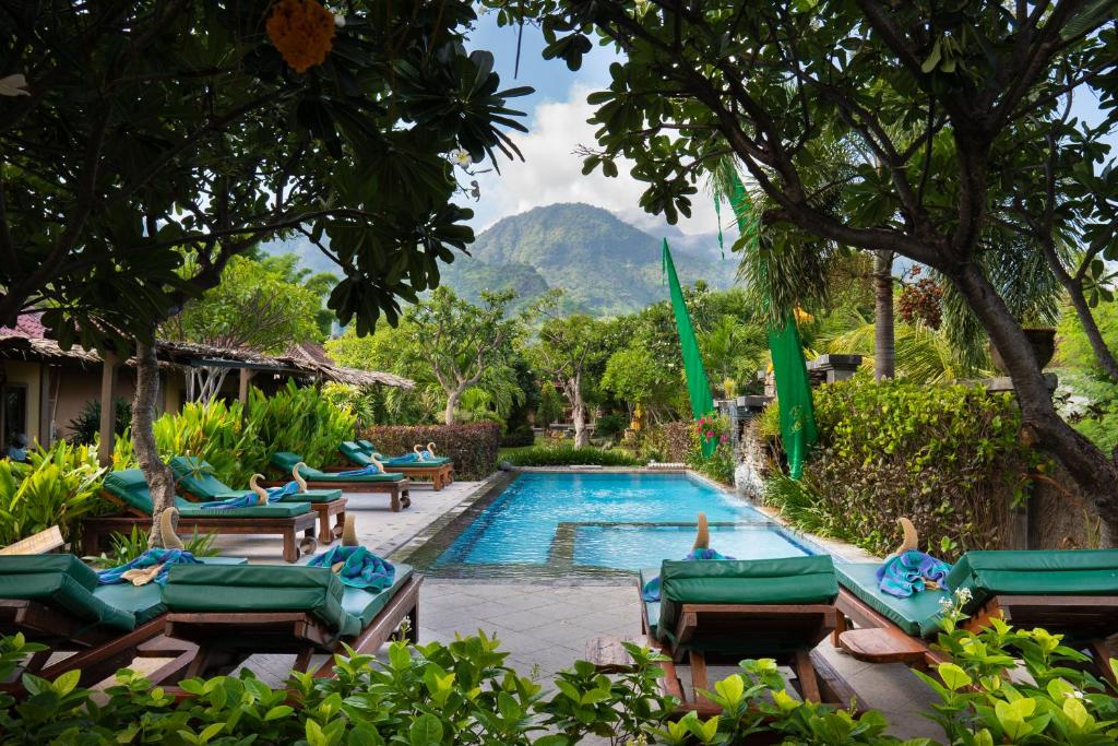 a swimming pool with lounge chairs and a resort at Taruna Boutique Homestay & Spa in Pemuteran