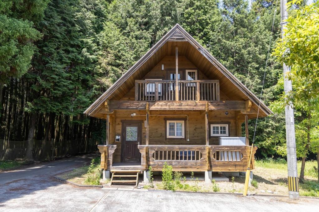 a log cabin in the woods with a porch at Mtd大分天ヶ瀬 in Hita