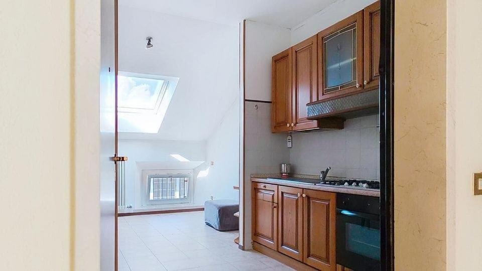 a kitchen with wooden cabinets and a stove top oven at Levico Old Town Loft in Levico Terme