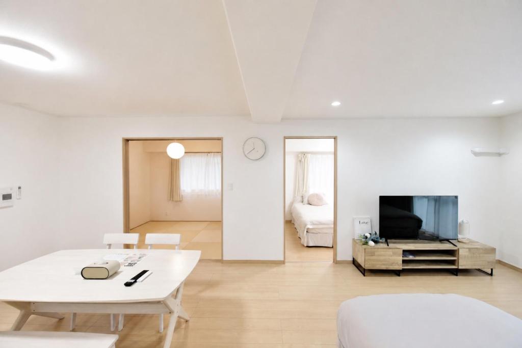a white living room with a white table and a tv at Room 501 Japanese Tatami 3LDK 75sqm Near Namba Family Friendly Stay in Osaka