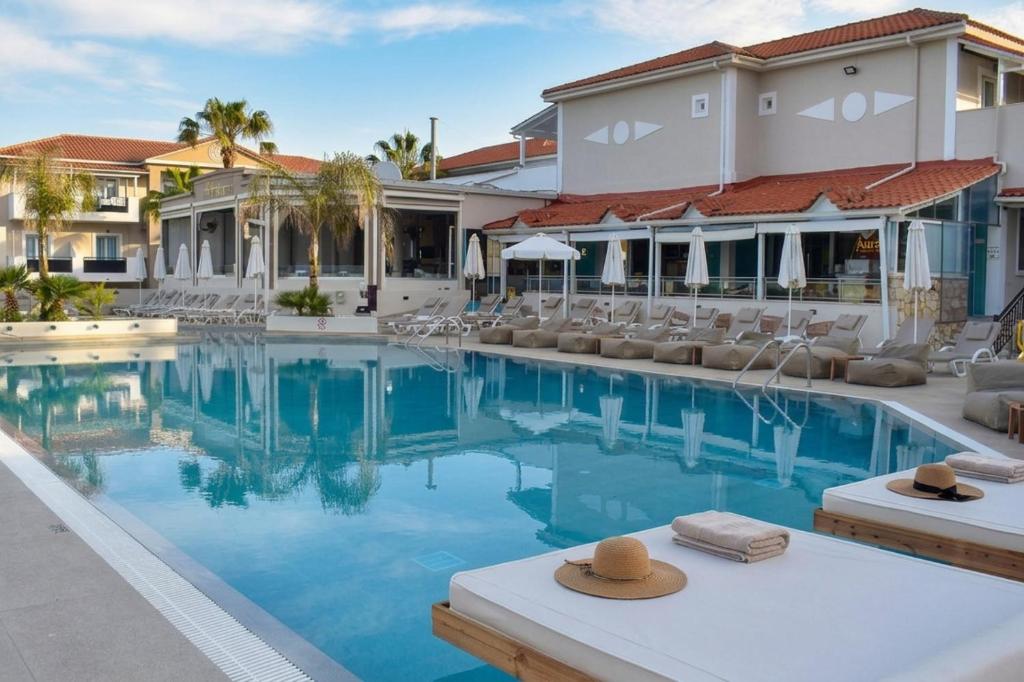 a pool at a resort with chairs and a building at Dennys Inn Hotel in Kalamaki