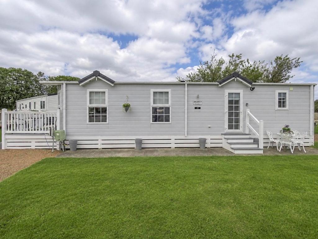 a white house with a porch and a lawn at Sunset Lodge in Warkworth