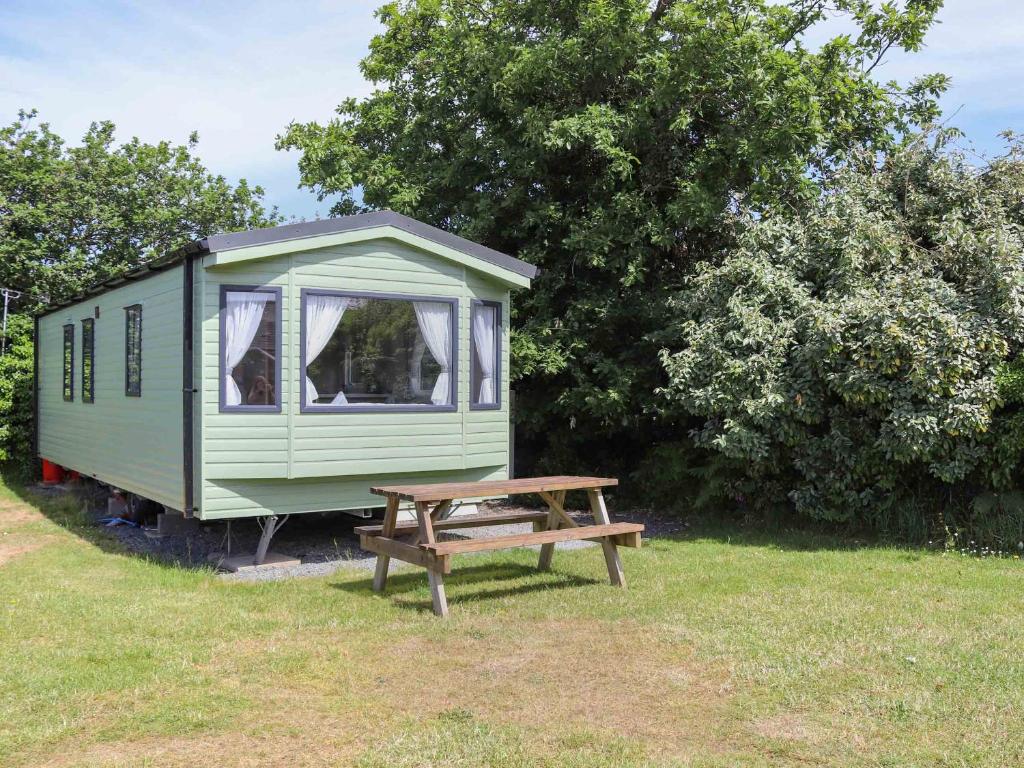a green campsite with a wooden bench and trees at Sarnfaen Static - Uk52097 in Llanddwywe