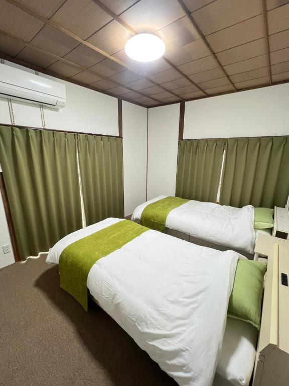 two beds in a room with green and white at 民泊びんご1 in Onomichi
