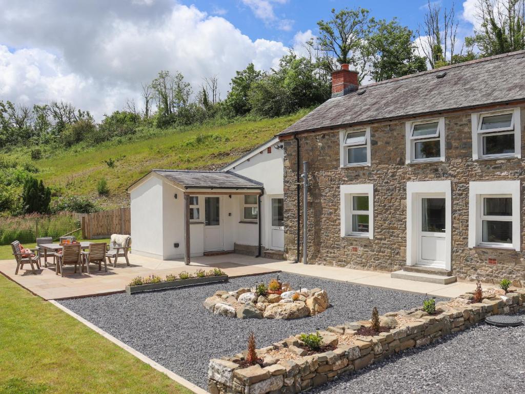 a stone house with a garden and a patio at Pantglas in Llandysul