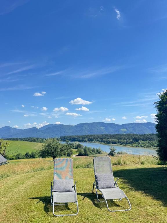 two chairs sitting on the grass next to a lake at LAKEview HAUS in Braslovče