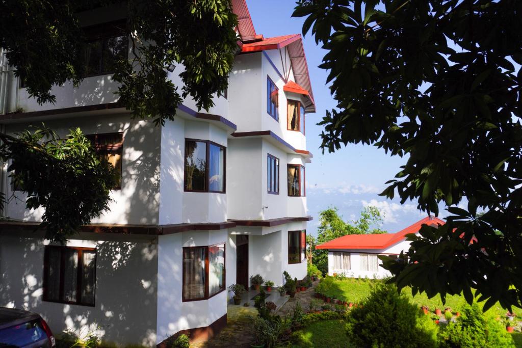 a white building with a red roof at Pine Haven Resorts in Takdāh