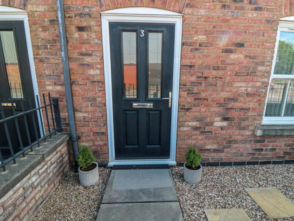 a black door on a brick building with two potted plants at 3 Railway Terrace in Bridlington