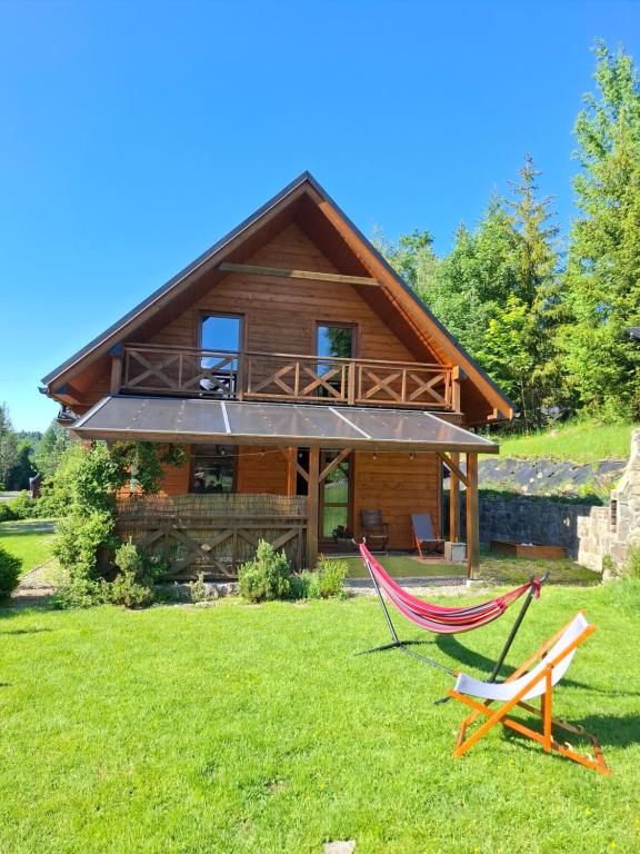a log cabin with a hammock in front of it at Agroturystyka "Domek pod Praszywką" in Rycerka Górna