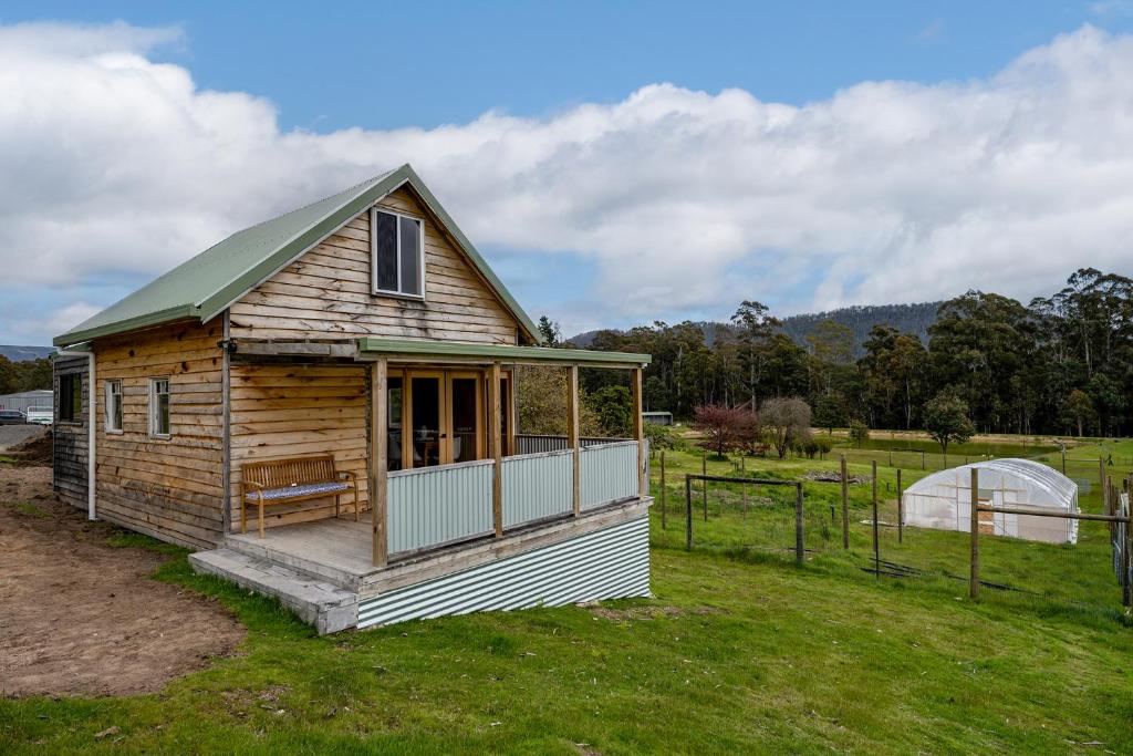 a small wooden house in a field of grass at Rivendell Cottage - Off Grid cabin in Jackeys Marsh