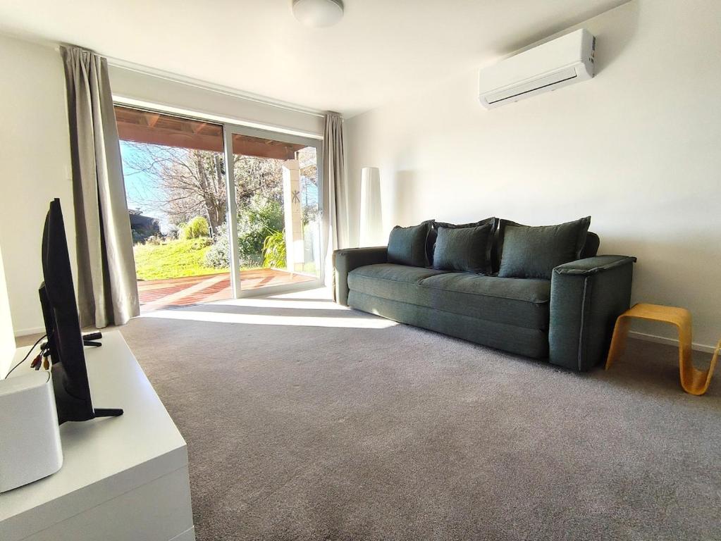 a living room with a green couch and a television at Dark Sky Retreat in Lake Tekapo