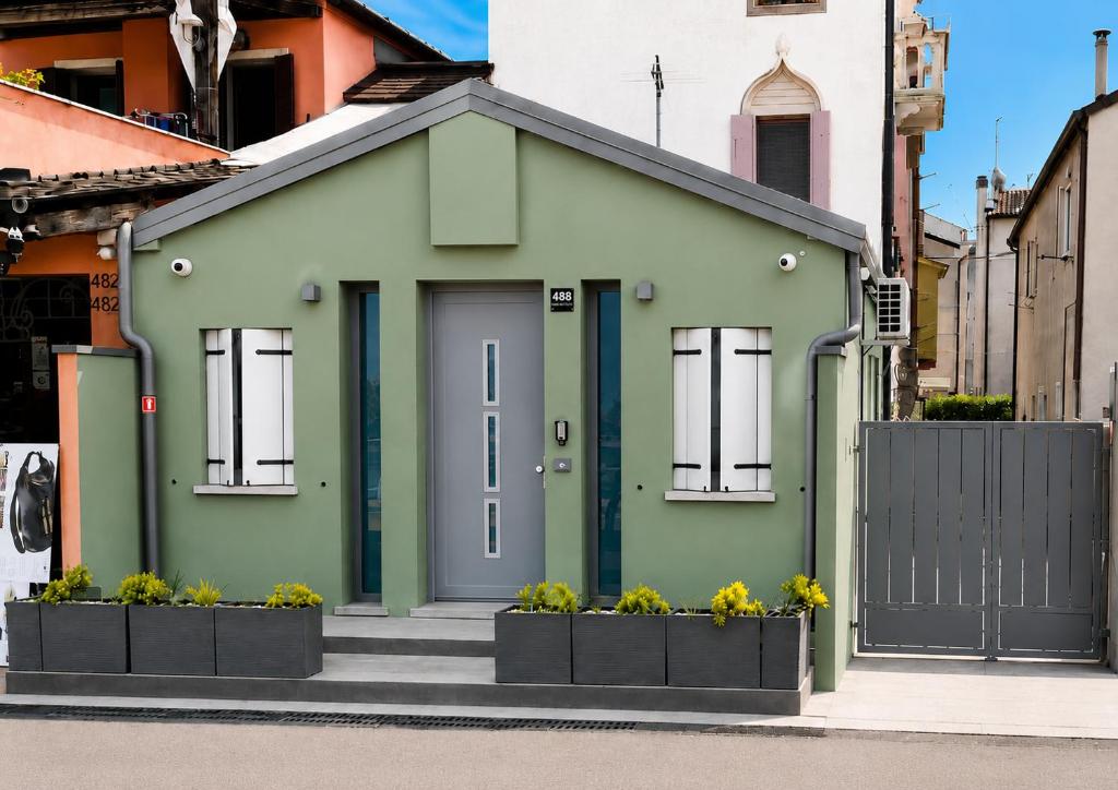 a green house with a door in a street at Cà in Laguna in Chioggia