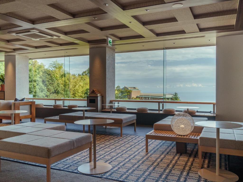 a lobby with tables and chairs and large windows at Soratoniwa Atami Izusan in Atami