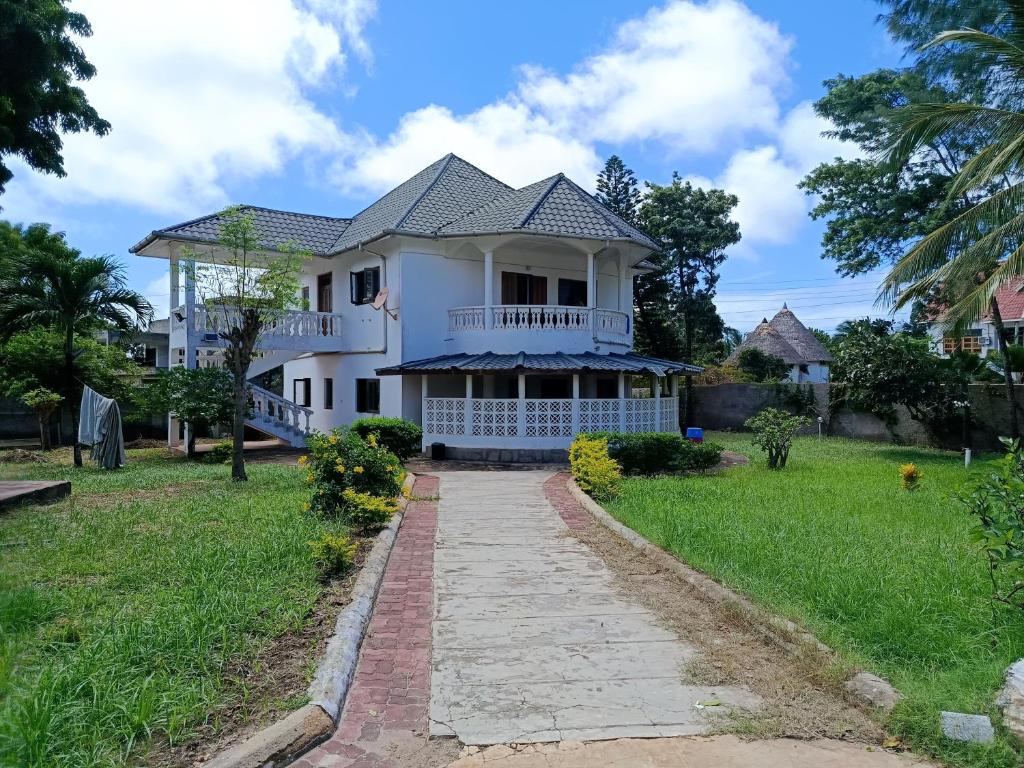 a white house with a walkway in front of it at Diani family friendly in Diani Beach