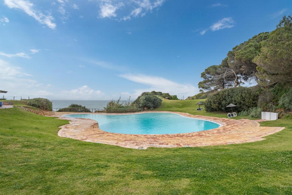a swimming pool in the middle of a grass field at Prainha Lounge in Alvor