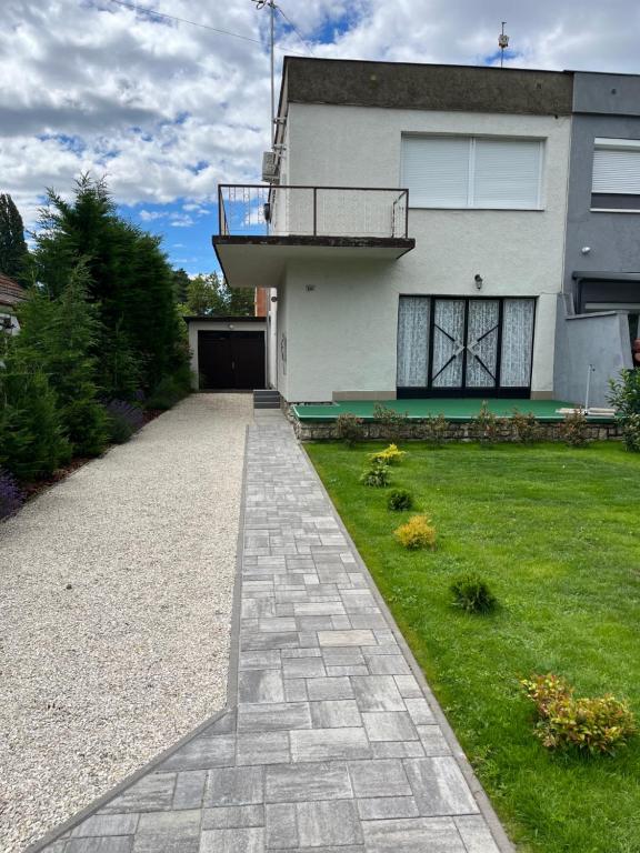 a house with a walkway in front of a yard at Vasút 10 in Balatonlelle