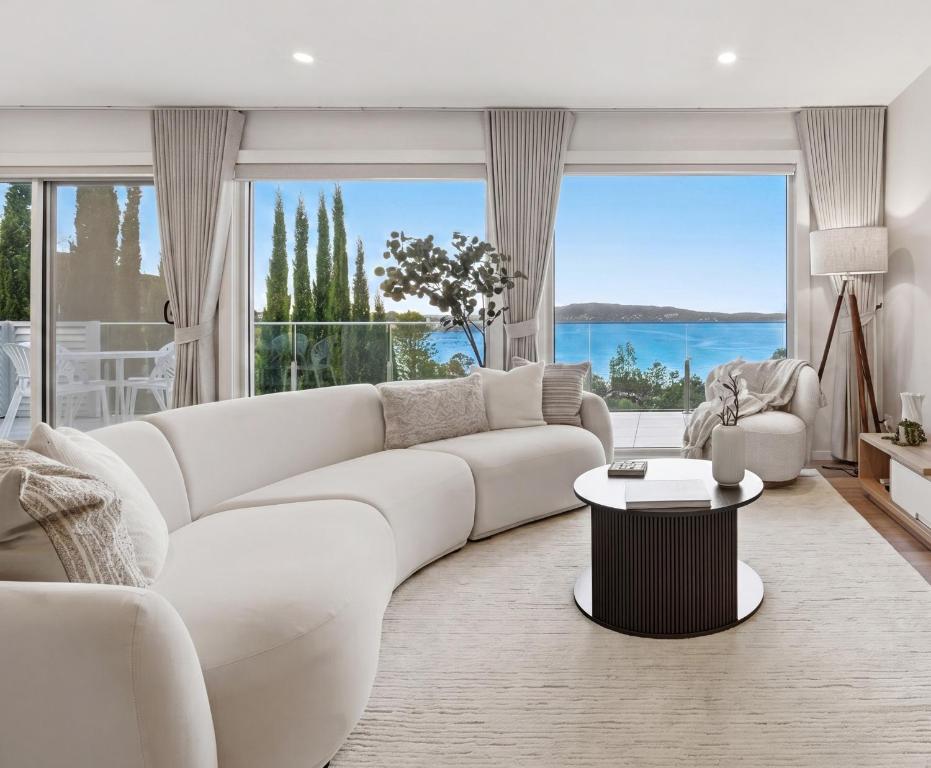 a living room with a white couch and a large window at Bayview Luxe Retreat in Tascott