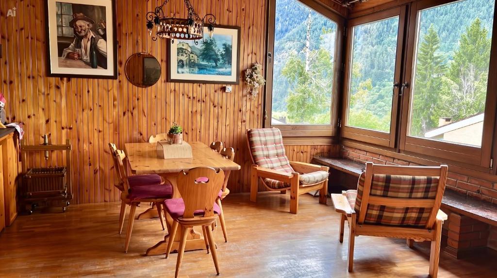 a dining room with a table and chairs and windows at Chalet Costa Rotian in Commezzadura