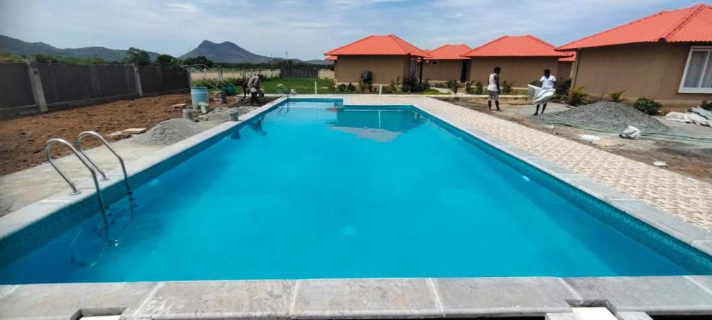 a blue swimming pool with people standing around it at Anaasa Resorts in Tiruvannāmalai