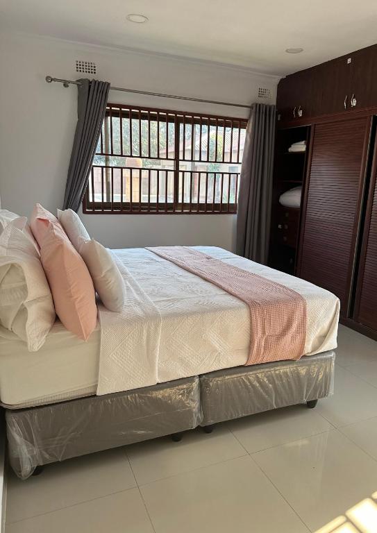 a bedroom with a bed with pillows and a window at JAYNIEL Apartments in Lusaka