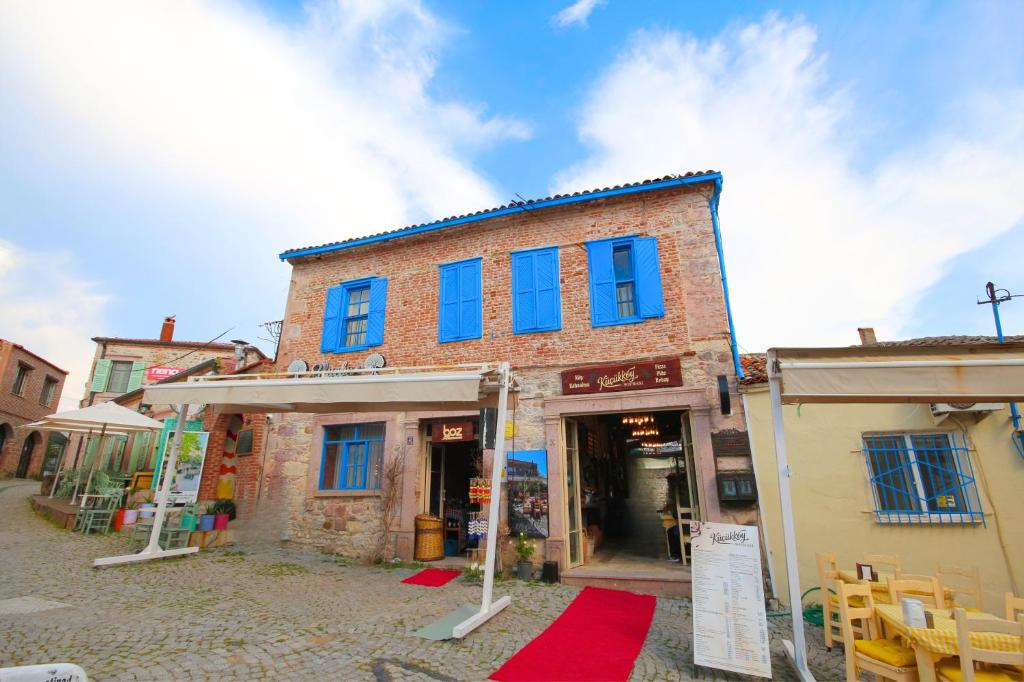 an old brick building with blue windows on a street at Blue Boz Küçükköy in Ayvalık