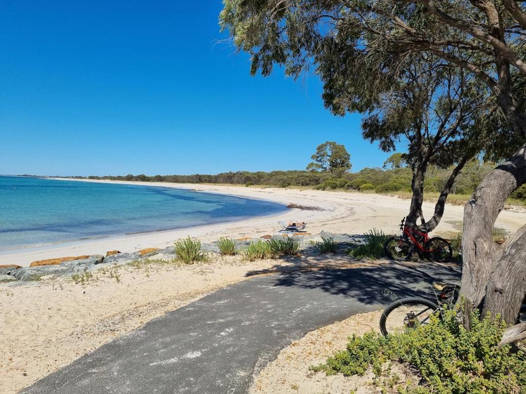 a bike parked on a beach next to the ocean at Barnard Beach House in Broadwater