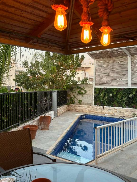 a patio with a swimming pool under a roof with lights at Seana Hidden Gem in Kapparis in Paralimni