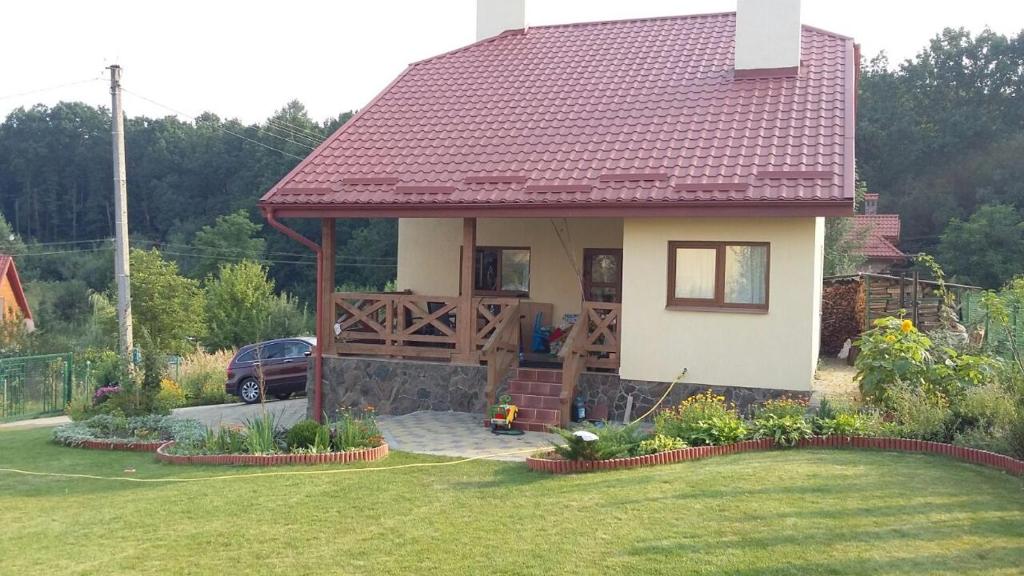 a small house with a red roof and a yard at БУДИНОК сімейних ПРИГОД in Vodniki
