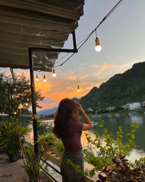 a woman looking out at a lake at sunset at Phong Nha Riverview Home in Phong Nha