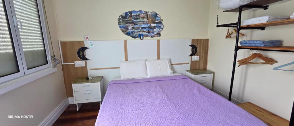 a bedroom with a bed with a purple blanket at BRUMA HOSTEL in Ponta Delgada